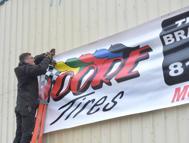 Kyle Moore secures a Moore Tires banner to the business' new location on Tuesday, Feb. 6, 2024. The longtime business is relocating to a new location after a fire last month destroyed its Rock Falls location.