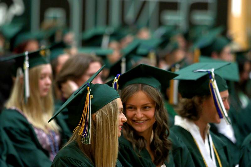 Quinn Feehery, left, shares a laugh with Emily Fehlberg as they wait too line up for York High School’s graduation at the school in Elmhurst on Sunday.