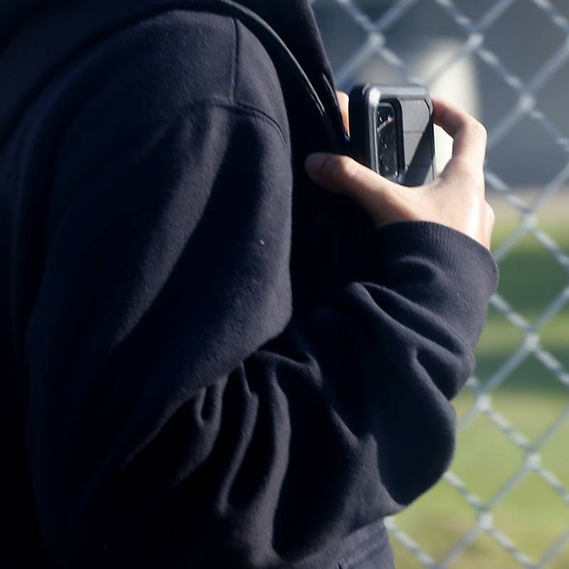 A student holds a cellphone while walking toward Woodstock High School on Wednesday, Aug. 14, 2024, for the first day of school.