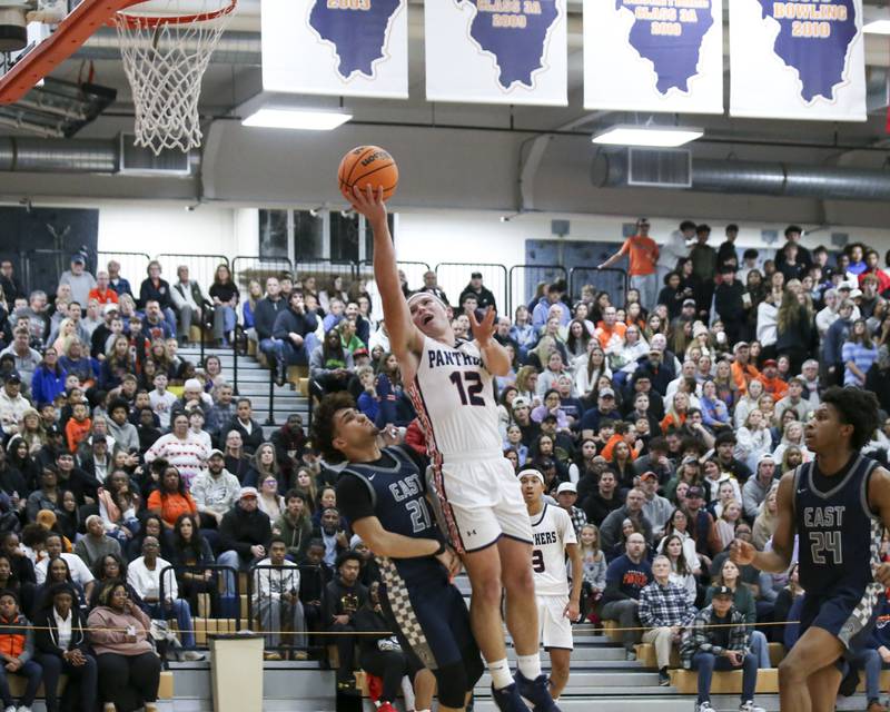 Oswego's Graham Schwab (12) draws a blocking foul during their basketball game between Oswego East at Oswego Friday, Jan 9, 2026 in Oswego.