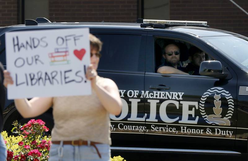 A McHenry police officer watches as people  protest along Route 31 in front of the McHenry Public Library on Friday, June 20, 2025, during a Save Our Libraries Protest hosted by Indivisible McHenry County to draw attention to cuts to the nation’s libraries by the Trump administration.