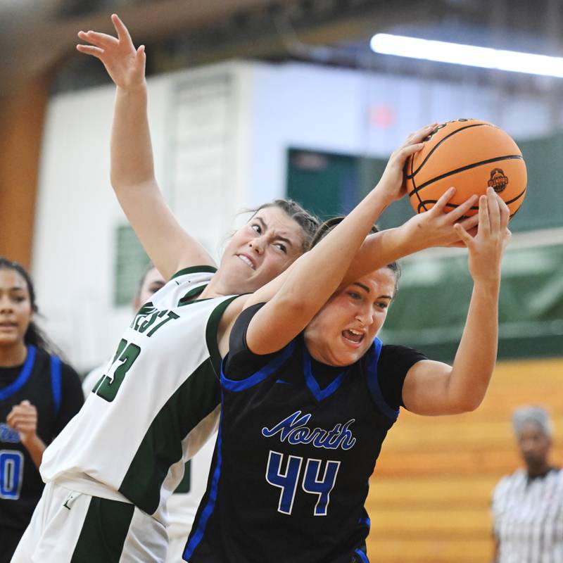 Glenbard West’s Makenna Yeager, left, and St. Charles North’s Riley Barber battle for a rebound during Thursday’s game in Glen Ellyn.