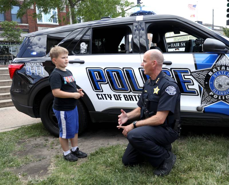 Batavia Police Chief Shawn Mazza chats with Bronson Wing, 7, while handing out coupons for free ice cream scoops outside the Batavia Creamery on Thursday, June 6, 2024.