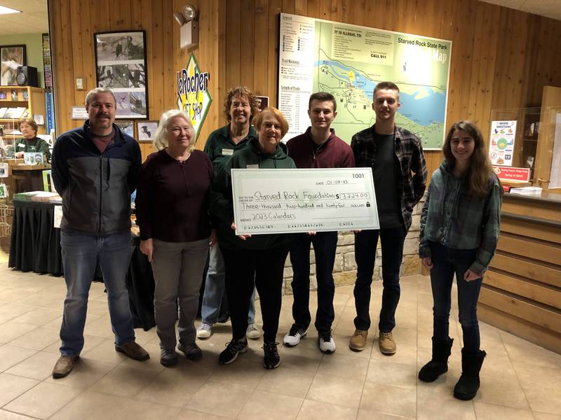 People involved in the Starved Rock Calendars project created by Matthew Klein pose for a photo at a check presentation ceremony Sunday, Jan 8 at the Starved Rock Visitor Center.