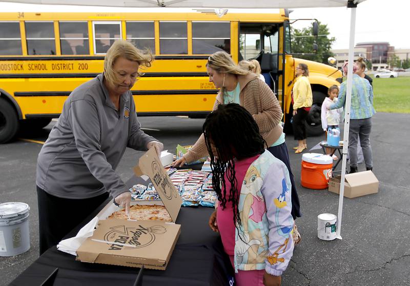 Pizza is handed out to children during a Woodstock School District 200 Back to School Coming to You event at Northwood Middle School on Tuesday, Aug. 6, 2024. The location was one of twelve stops on the tour that gave out backpacks and school supplies, provided registration help and computer repair.