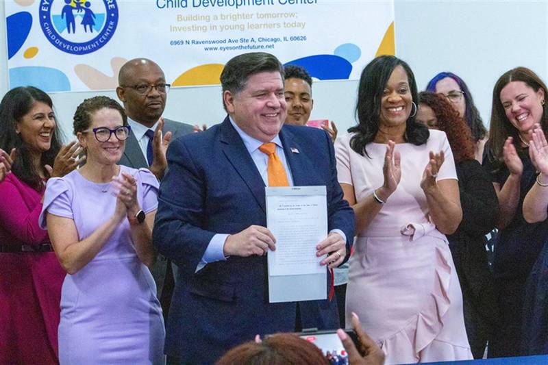 Gov. JB Pritzker holds up Senate Bill 1 after signing it into law, flanked by Reps. Mary Beth Canty, D-Arlington Heights, and Will Davis, D-Homewood (left) and lead Senate sponsor Sen. Kimberly Lightford, D-Maywood (right). Pritzker said the agency is expected to be up and running in 2026.