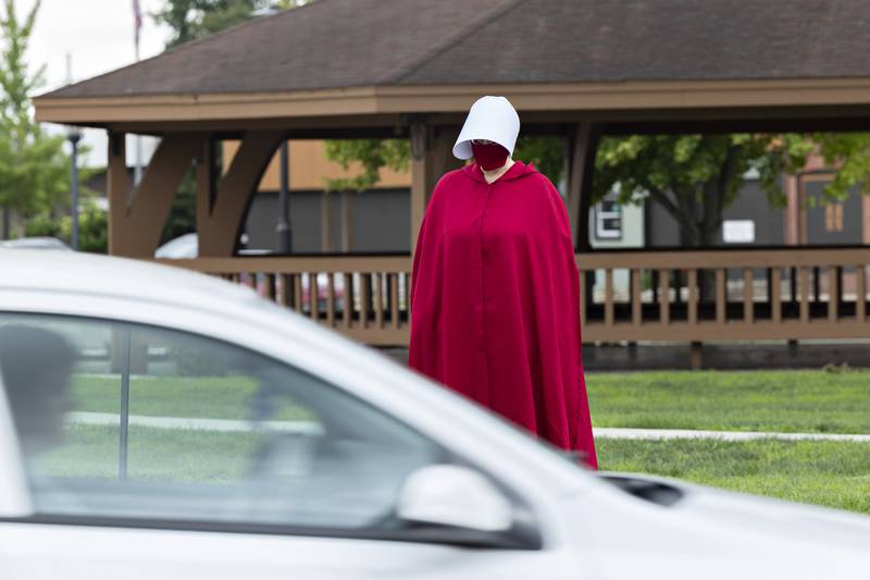 A protester, dressed as a character from the show “A Handmaid’s Tale,” is seen along East Fourth Street in Sterling Thursday, July 17, 2025. The Sterling protest was part of a nationwide gathering.