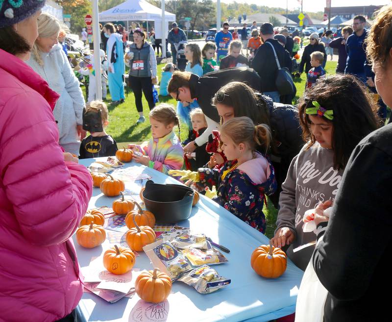 Children choose a pumpkin to decorate from The Batavia Mothers’ Club’s booth at Batavia’s Batfest on Saturday, Oct. 30, 2021.