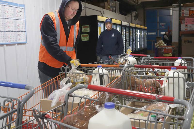 Kevin Ballard and George White prepare cart fulls of food during the Thanksgiving distribution on Wednesday, Nov. 19, 2025 at the Hall Township Food Pantry in Spring Valley. Nearly 500 families will receive food from this years distribution.