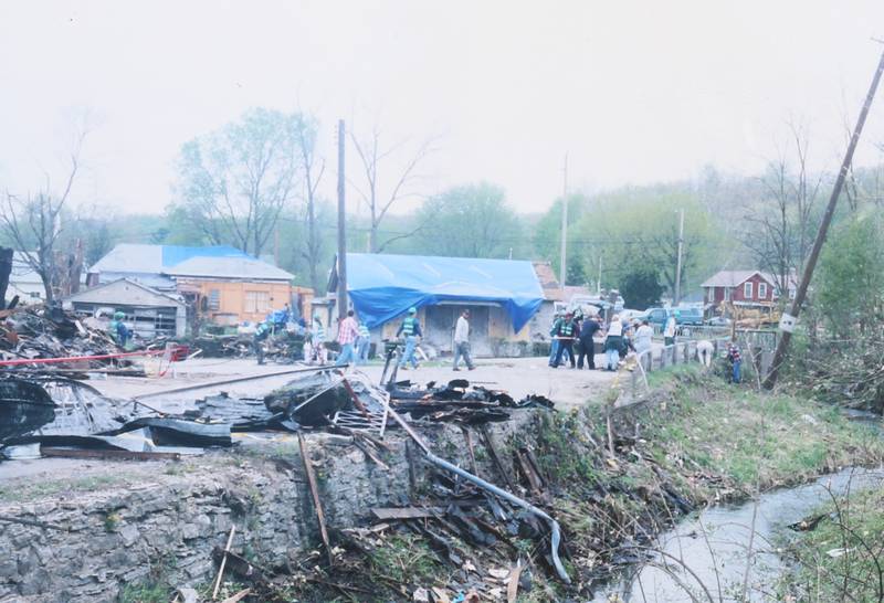 United States Postal Service workers help clean up tornado debris from Clarks Run Creek on Wednesday April 21, 2004 downtown Utica.