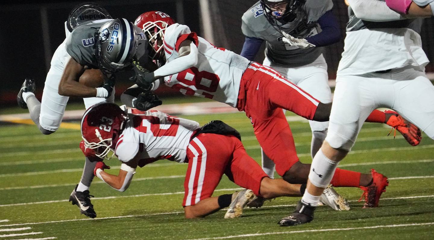 Yorkville's Dom Recchia (23) and Bryce Griffin (28) tackle Oswego East's Andre Cobige Jr. (3) during a football game at Yorkville High School on Friday, Oct. 13, 2023.