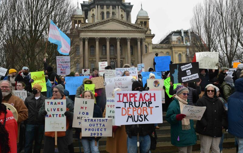 Protesters hold signs and chant in front of the Illinois State Capitol to protest President Donald Trump's administration on Wednesday