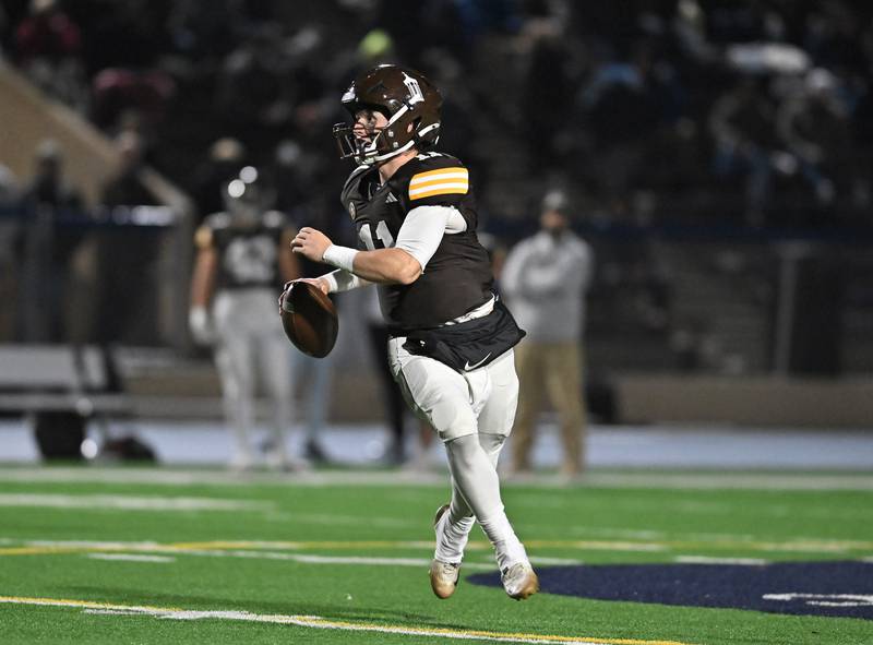 Joliet Catholic's Lucas Simulick (11) rolls out looking to throw a pass during the conference game against Providence Catholic on Friday, OCT. 24, 2025, at Joliet.