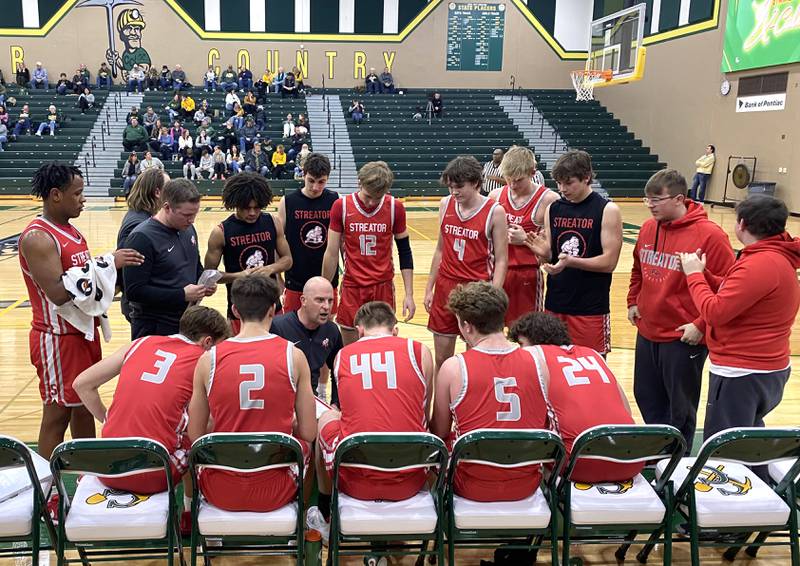 Streator boys basketball head coach Beau Doty (kneeling at center) instructs his Bulldogs during a timeout Tuesday, Jan. 28, 2025, at Coal City.