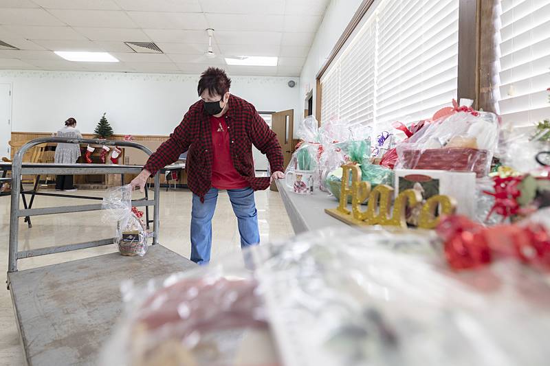 Volunteer Kathi Johnson sets up more items in Santa's Secret Workshop, where clients with developmental disabilities at Rock River Valley Self Help Enterprises can shop in safety and security.  Any leftover items are given as gifts to local nursing homes and the money that is raised goes toward a fun day in the summer; all money stays within the facility.