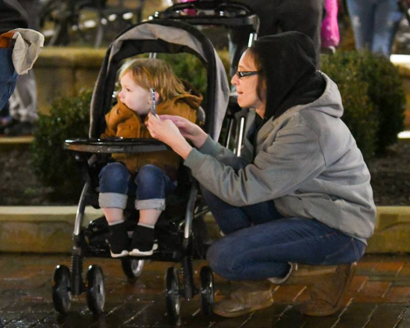 Jackie Belmont records Santa during a tree lighting ceremony while her son, Kash Shields, 2, of DeKalb watches during the DeKalb Chamber of Commerce's annual Lights on Lincoln and Santa Comes to Town event held in downtown DeKalb on Thursday, Nov. 30, 2023.