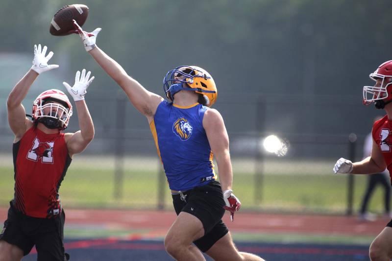 A Lyons Township player (right) reaches for a pass during a 7-on-7 football tournament game against Maine South at West Aurora High School on Friday, June 23, 2023.