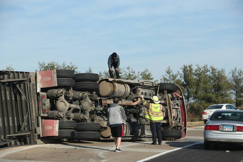 A semi truck driver stands on top of his truck that rolled over as La Salle firefighters prepare to rescue him on the west on ramp to Interstate 39 on Friday, Dec. 2, 2022 near La Salle. La Salle and Utica fire and EMS were dispatched to the scene. The incident happened shortly before 9:30a.m.