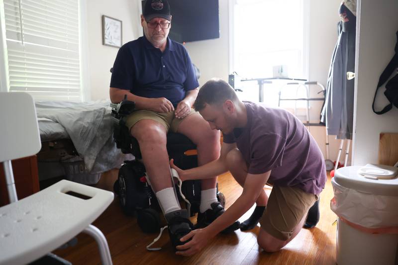 Sean Flannery helps his father, Tim, remove his brace. Nearly a year after Tim’s motorcycle accident that left him in critical condition, Tim is still recovering with the help of his son and wife. Wednesday, June 15, 2022 in Joliet.