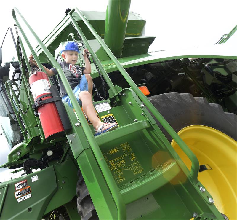 Noah Leipold carefully climbs down from this John Deer combine Sunday, July 28, 2024, during the Touch A Truck event in Ottawa.