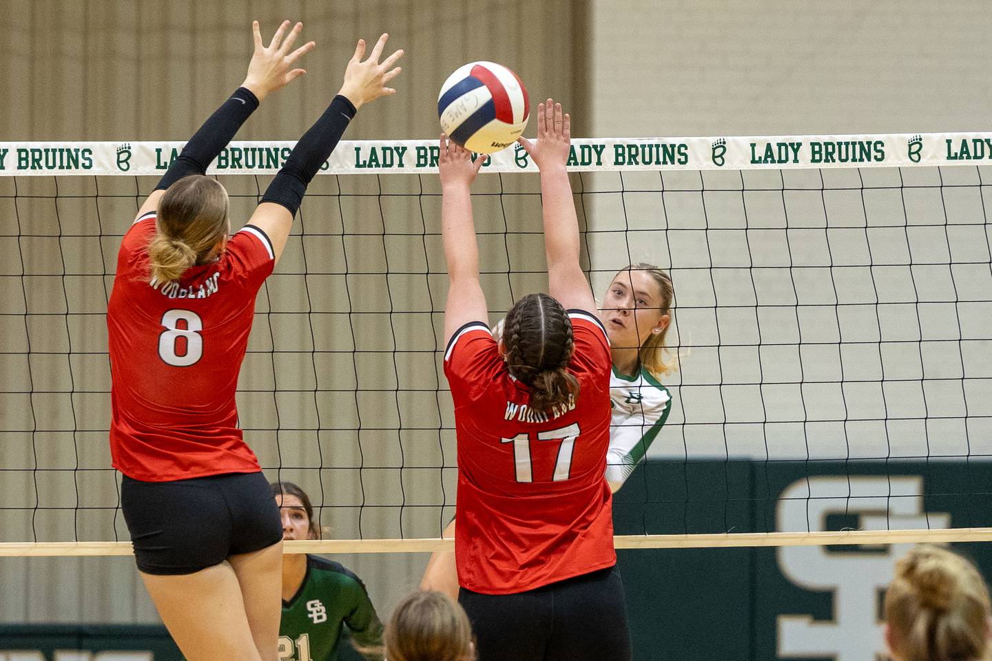 Grace Longmire (8) of Woodland and teammate Adrianna Kuehn (17) let ball slip through fingers as Nelle Potthoff of St. Bede sends ball over net on Thursday, Sept. 11, 2025 at Abbot Vincent Gymnasium in Peru.