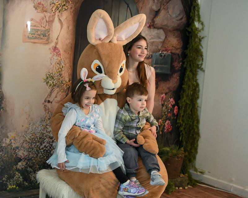 Siblings Avery, 5, and Aiden Wrolson, 3, of Downers Grove along with their cousin Ella Lowe, 12, of Oswego all pose for a photo with the Easter Bunny on Saturday April 12, 2025, during the annual bunny hop held in downtown Oswego.