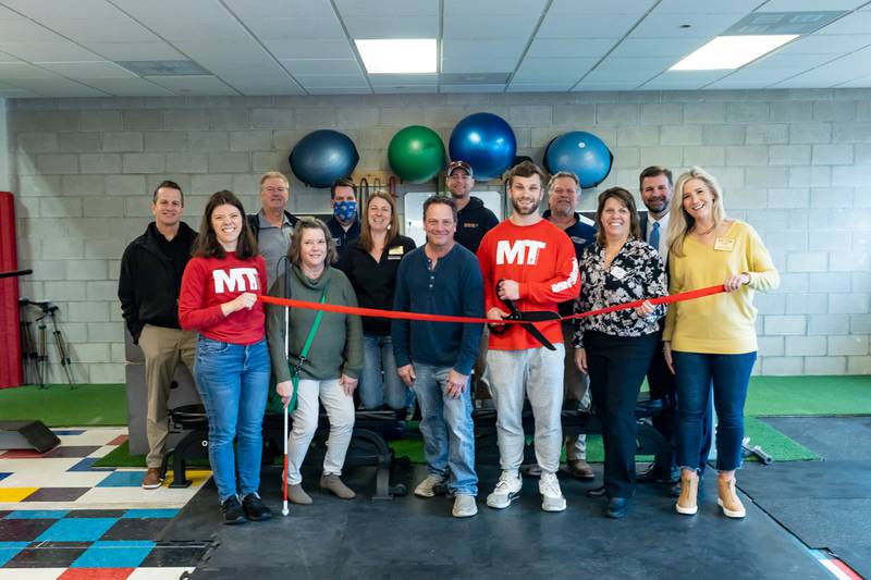 Marcus Thimios, owner of MT Performance, cuts the ribbon to celebrate a new location in Crystal Lake. He is joined by family, friends, and the staff and board members of the Cary-Grove Area Chamber of Commerce.