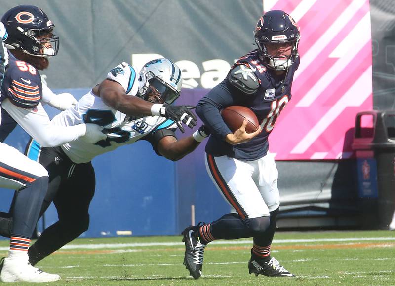 Chicago Bears quarterback Caleb Willams scrambles out of a sack as teammate Darnell Wright pushes Carolina Panthers offensive back Charles Harris away on Sunday, Oct. 6, 2024 at Soldier Field in Chicago.