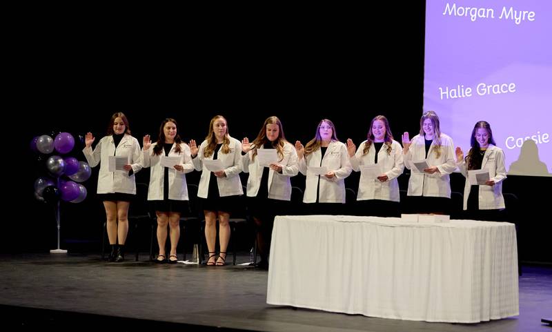 The first class of eight dental hygiene students to graduate from Illinois Valley Community College accepted white lab coats and lapel pins to signify their entry into the field during a ceremony on December 12, 2025.
