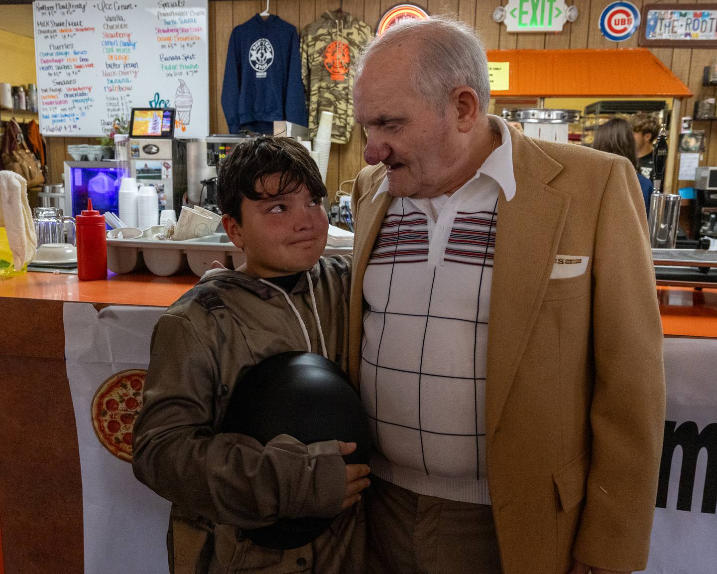 Jameson Walgenbach with tears in eyes looks up at Sam Leone at Sam’s retirement celebration on Saturday, October 25, 2025 at the Rootbeer Stand in Oglesby.