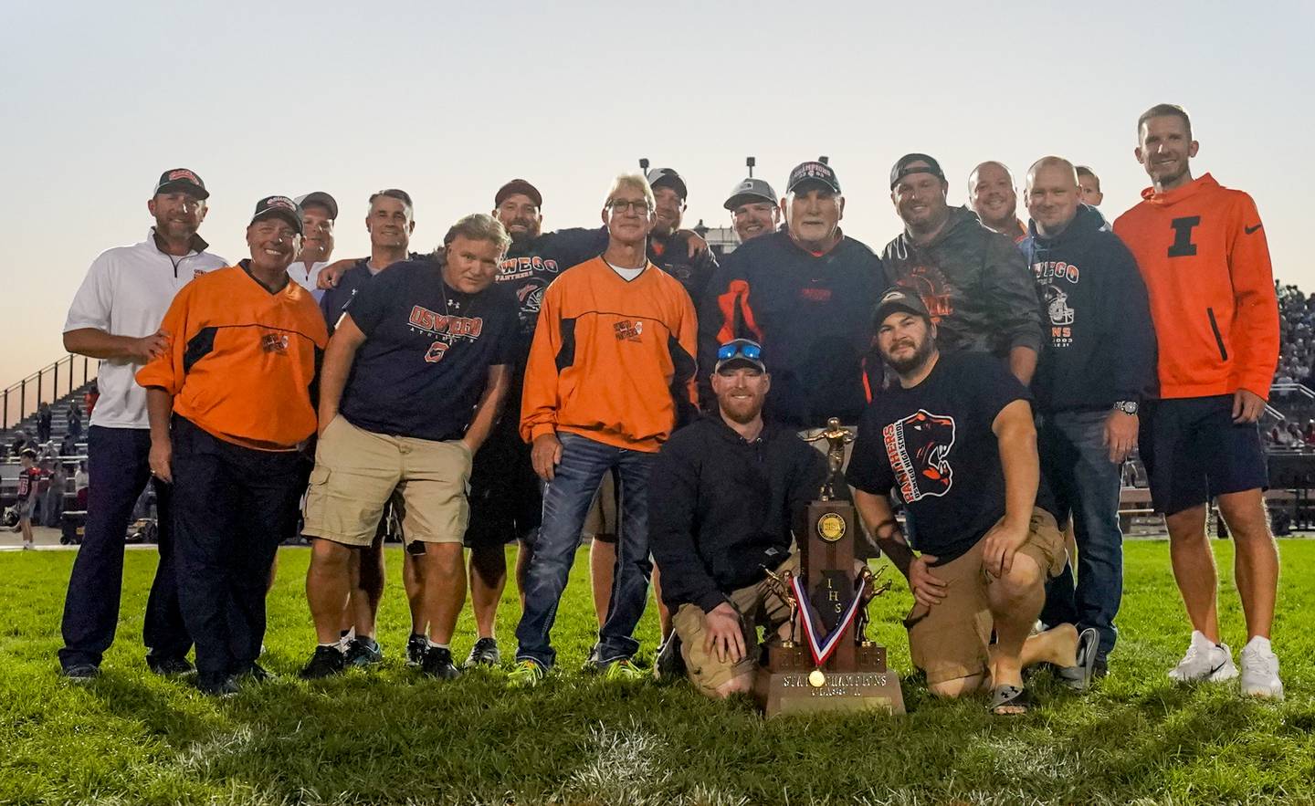 Oswego Alumni and coaches from the 2003 team that won the state championship pose for a photo on the 50 yard line prior to kick-off against West Aurora during a football game at Oswego High School on Friday, Sept. 29, 2023.