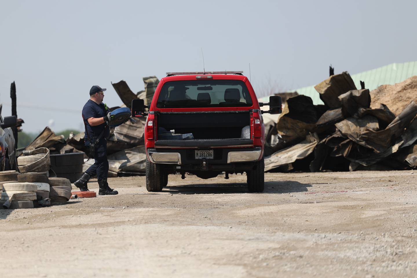 A Beecher fire fighter loads hoses in a truck after a fire at a horse ranch Wednesday, May 24, 2023, in Beecher.
