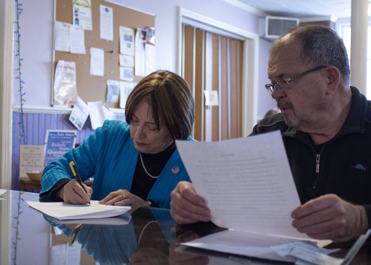 Christine Benson, chair of the Ottawa Center for the Arts Board, signs the sale/lease agreement with Open Table United Church of Christ. Bob Eschbach (right) served as attorney for the church.
