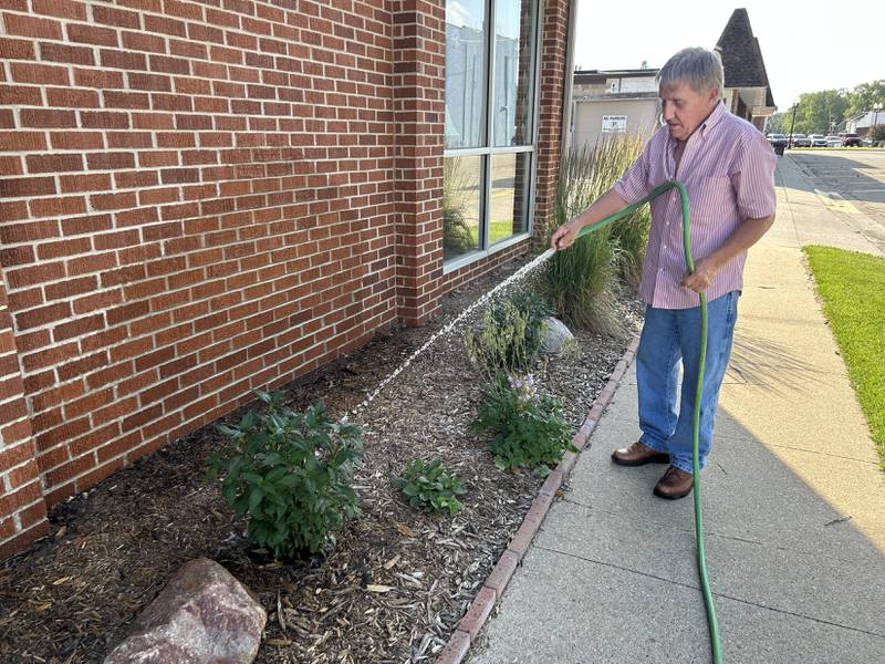 Curt Huizenga waters plants alongside the Erie Library on Saturday, June 21 as temperatures hit the mid 90s. Huizenga is a member of the library board.