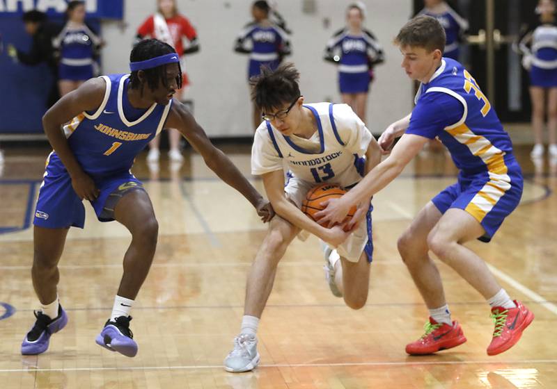 Woodstock's Joesph Nitz (center) tries to protect the ball as Johnsburg's Jarrel Albea (left) and JT Schmitt triy to steal the ball during a Kishwaukee River Conference basketball game on Friday,  Feb. 14, 2025, at Woodstock High School.