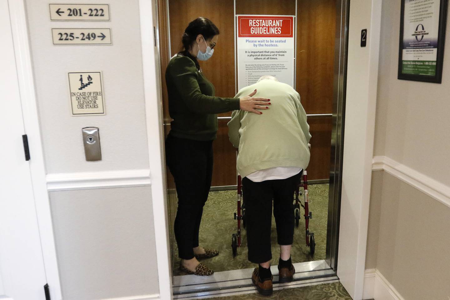 Ewa Kroupa, director of nursing, left, guides resident Rosemary Buttstadt onto the elevator to head down for breakfast Monday, Nov. 22, 2021, at Three Oaks Assisted Living and Memory Care in Cary.  The senior residence has been among many local employers having difficulties filling positions and keeping them filled. Many of the current employees, including upper management, pitch in with duties while understaffed.