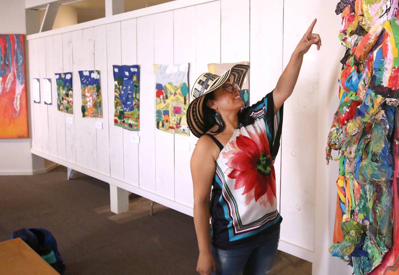 DeKalb resident Carolina Velandia talks about her work entitled “Dance, Love, and Art” Wednesday, Sept. 18, 2024, that is part of the Arts in Action exhibition at the Ellwood House Museum in DeKalb. The work behind her is by her mother Nohora S. Hernandez. The exhibit features work by local Latino artists and runs through the end of the year.