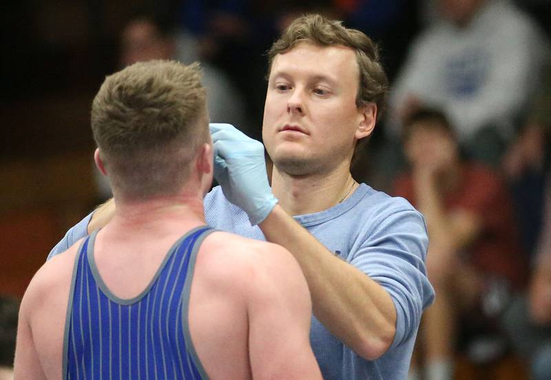 Brad Groleau (right) checks on Newman's Briar Ivey during a blood time out at  the 61st annual Lyle King wrestling tournament on Saturday, Jan. 11, 2024 at Princeton High School.  Groleau is a 2013 grad of St. Bede Academy and was a two-time Bureau County Republican Baseball Player of the Year and played at McKendree University. Groleau is now the Minor League Athletic Trainer for the Kansas City Royals.