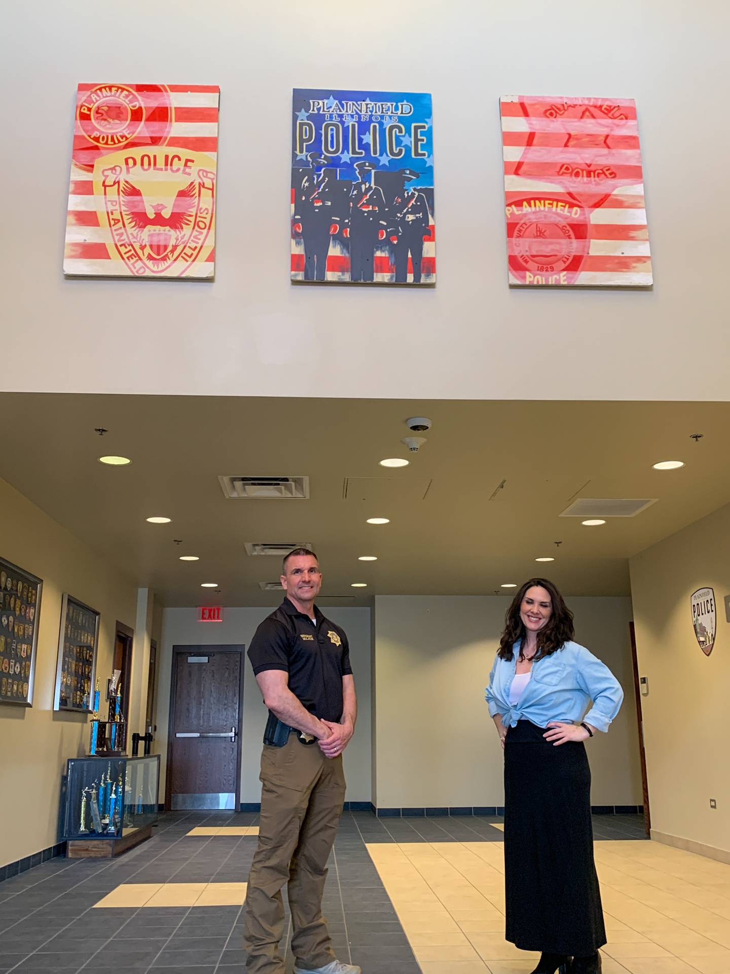 Plainfield Police Sgt. Colin Mulacek (left) and Plainfield High School-Central Campus art teacher Lindsey Brown pose with Brown's artwork in the police department's Branch Court lobby. Brown designed and painted the three-panel mural at the department's request.