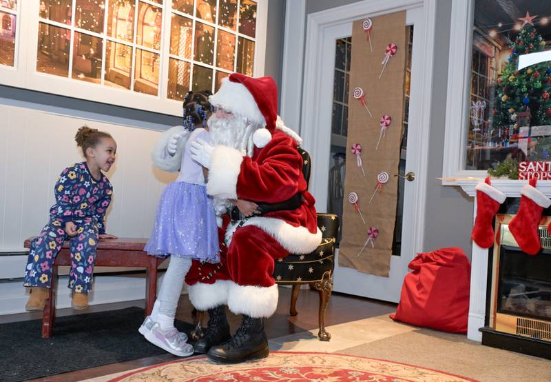Norah Stob, 6 gives Santa a hug as her sister Scarlett, 3 looks on as they visit Santa at the Geneva Visitor Center on Saturday, Dec 20, 2025 in Geneva.