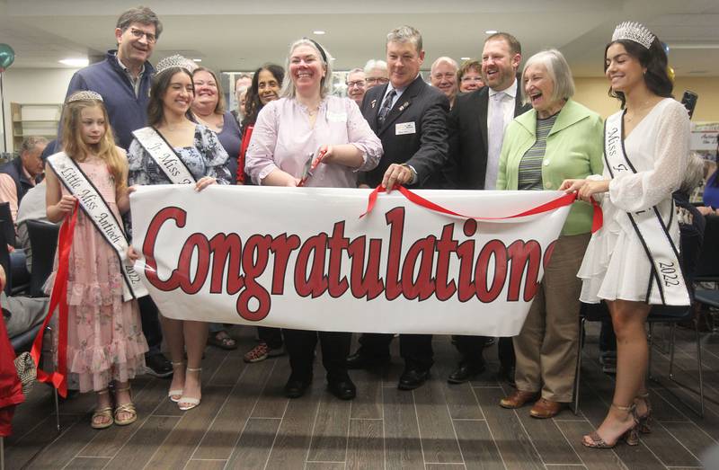 Jennifer Drinka, library director, (center) stands next to Paul Hettich, library board president, as she cuts the ribbon Saturday, May 13, 2023, with everyone around her including the Antioch queens, Antioch Chamber, Library Board Past, Present & Future, Woman's Club and legislators during the Antioch Public Library District Open House Ribbon Ceremony in Antioch. The ribbon ceremony was to celebrate the renovation and expansion of the library and it's 101st anniversary.