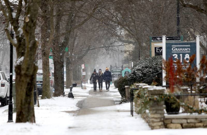 Shoppers walk down 3rd Street in Geneva during a snow storm on Thursday, Dec. 22, 2022.