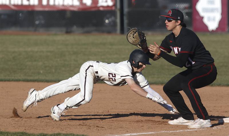 Prairie Ridge’s Riley Golden dives back to first base in front of the throw to Huntley’s CJ Filipek during a Fox Valley Conference  baseball game Wednesday, April 12, 2023, at Prairie Ridge High School.