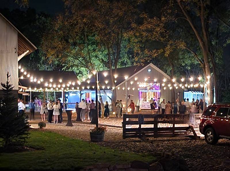 People attend a celebration under the lights at Deer Ridge Barn.
