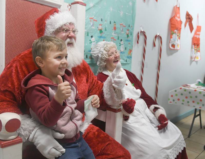 Asher James, 4, of Byron gives a thumbs up sign as he poses for a photo with Santa Claus and Mrs. Claus in Conover Square during Oregon's Candlelight Walk on Nov. 26.