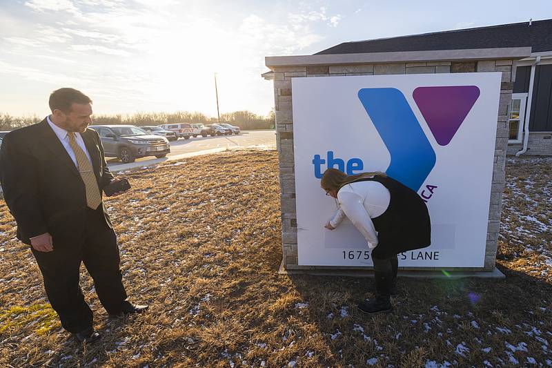 YMCA Child Care Center Director Heather Grobe pulls tape off the sign Wednesday, Jan. 15, 2025, at the new facility.