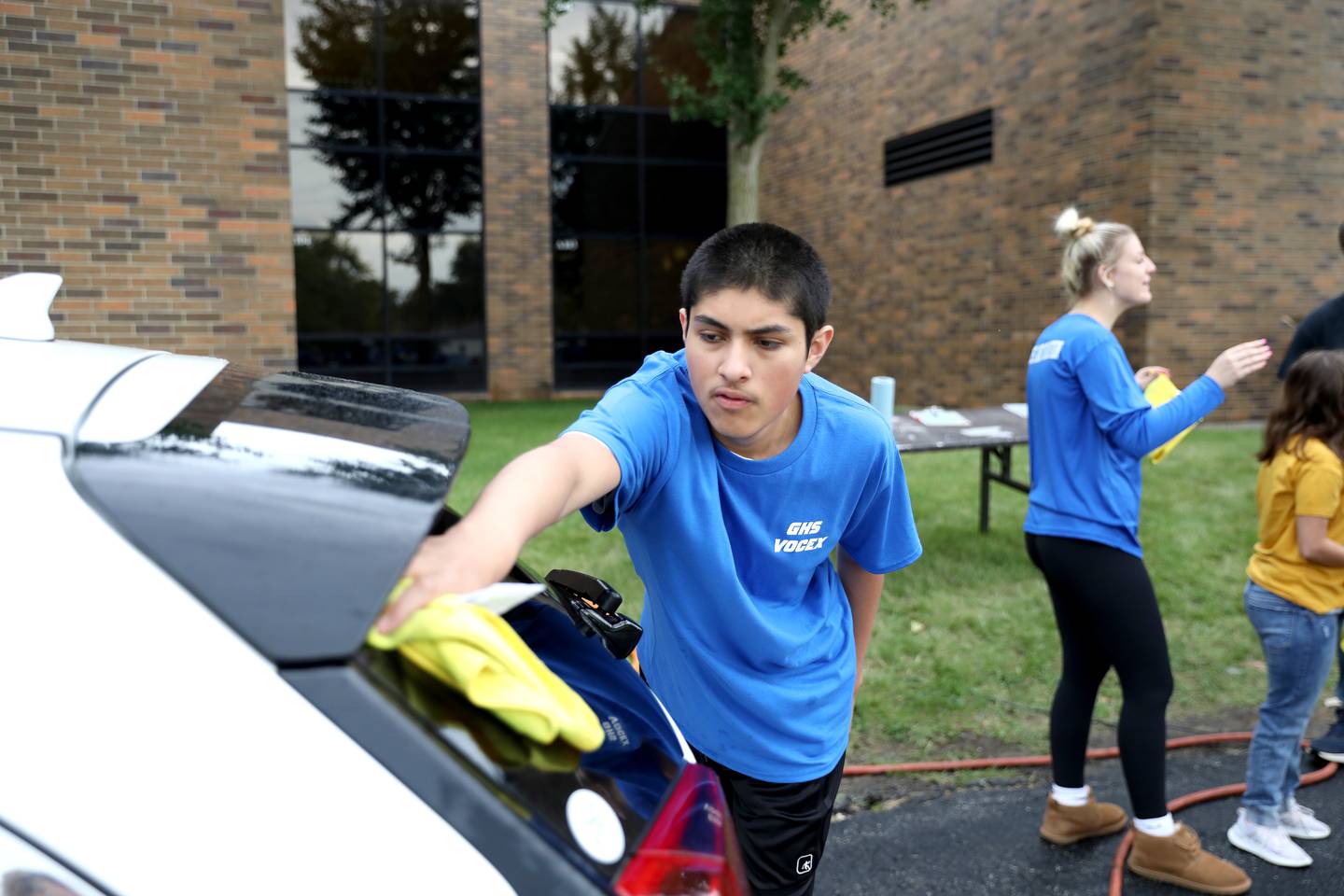Geneva High School student Jesus Villa Ortiz dries the back window of a car as part of the school’s Vocational Exploration program’s car wash day on Thursday, Sept. 21, 2023.