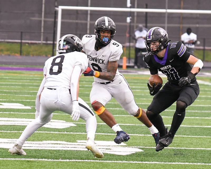Downers Grove North's Charlie Cruse, right, runs the ball after catching a pass for some extra yards during the second week of the class 7A game before being brought down by Fenwick's Jake Thies (8) on Saturday Nov. 9, 2024, held at Downers Grove North High School.