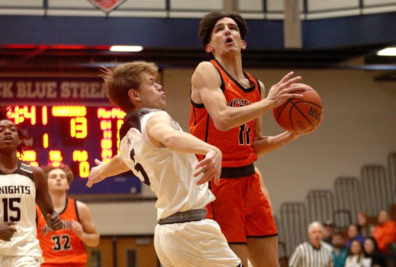 McHenry’s Hayden Stone goes to the hoop past Kaneland’s Bradley Franck, left, in Hoops for Healing basketball tournament championship game action at Woodstock Wednesday.