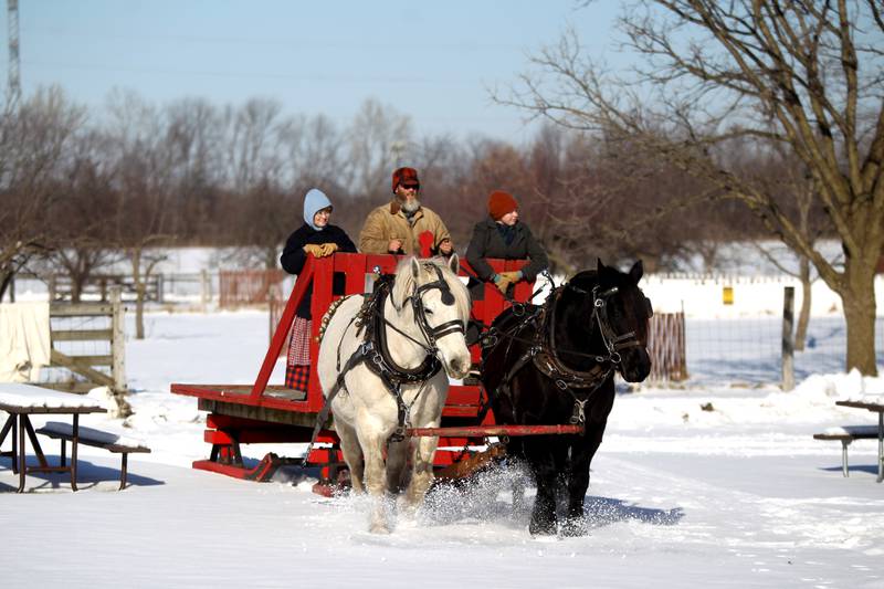 Matt Dehnart, historical farming program specialist, leads draft horses Bob (right) and Paul as Lisa Carpenter, historical farming program coordinator ((left) and Emaly Allison, heritage interpreter, ride the bob sled alongside him through Kline Creek Farm in West Chicago. The farm offers its Farmlife in Winter program Thursdays through Mondays.